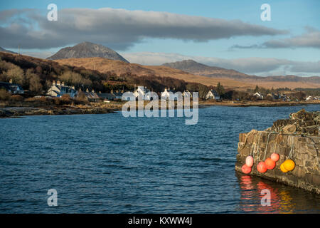 Schottische Häuser Punktierung der Küstenlinie von craighouse mit der paps von Jura als Hintergrund, Isle of Jura, Schottland Stockfoto