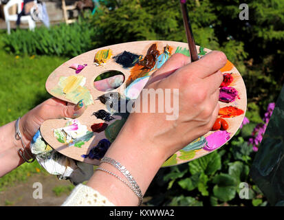 Die Hände des Künstlers in der Vorbereitung von Ölfarben auf eine Palette Stockfoto
