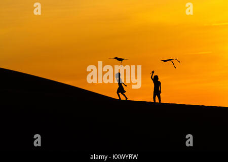 Früh morgens bei Sonnenaufgang. Kinder spielen mit Drachen in den Sanddünen in der Nähe von Phan Rang, central Vietnam Stockfoto