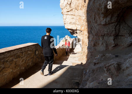 Touristen zu Fuß auf Treppe inmitten von Capo Caccia Klippen. Alghero, Sardinien, Italien Stockfoto