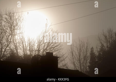 Sonne durch den Nebel über Häuser an einem nebligen Tag in Großbritannien brechen Stockfoto