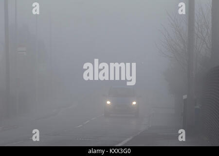 Auto fahren auf vorstadtstraße ohne foglights durch Nebel an einem nebligen Tag im Vereinigten Königreich Stockfoto