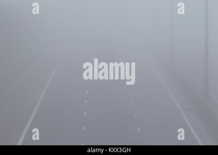 Kaum sichtbare Pkw fährt auf der Autobahn ohne foglights an einem nebligen Tag im Vereinigten Königreich Stockfoto