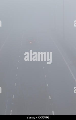 Einziges Auto fahren auf Autobahn mit Nebelscheinwerfer an einem nebligen Tag in Großbritannien beleuchtet Stockfoto