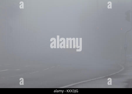 Auto mit Scheinwerfern auf der Fahrt auf schlechter Straße an einem nebligen Tag im Vereinigten Königreich Stockfoto