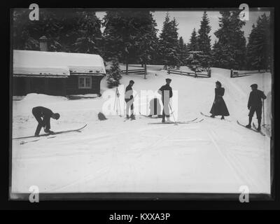Die Winterszene mit dem Titel „Frognersæteren Vinterparti“ zeigt das Gebiet von Frognersæteren in Norwegen unter Schnee und zeigt bewaldete Hänge, eine rustikale Hütte oder Hütte, Skipisten oder Wintererholung in der Landschaft bei Oslo. Stockfoto