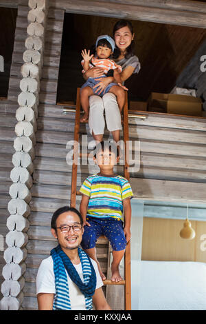 Familie, Mann, Frau, Junge und Mädchen sitzen auf einer Leiter, einem Lächeln auf die Kamera. Stockfoto