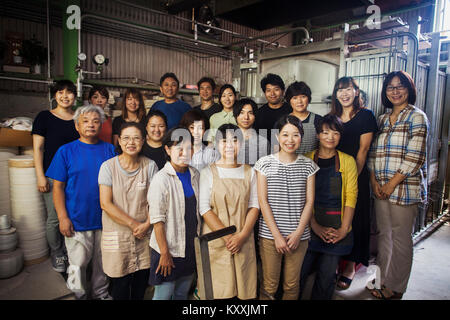 Gruppenbild der Mitarbeiter eines japanischen Porzellan Werkstatt stand vor der Brennofen, in die Kamera lächeln. Stockfoto