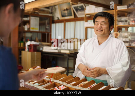 Verkäufer tragen weiße Kimono im Shinto Schrein Sakurai, Fukuoka, Japan. Stockfoto