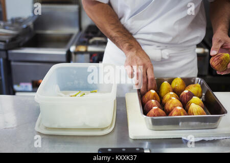 Hohen Winkel schließen, bis der Koch in der Küche eines japanischen Sushi Restaurant arbeiten, Feigen vorbereiten in einem Metallauflagefach aus. Stockfoto