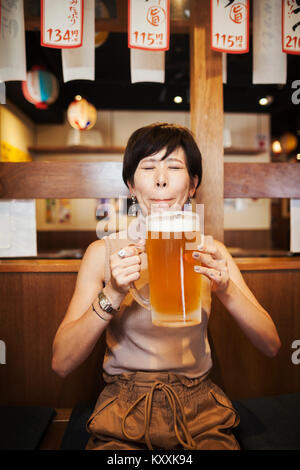 Frau sitzt an einem Tisch in einem Restaurant, große Glas Bier. Stockfoto