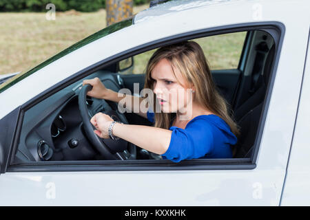 Expressive junge Frau das Auto fahren und sie schaut auf eine Wand zu spät Stockfoto