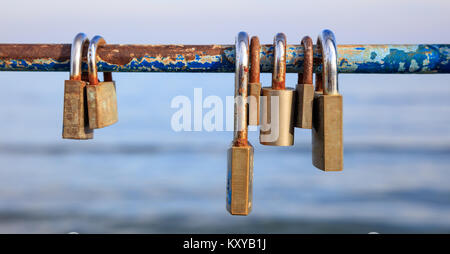 Rusty Vorhängeschlösser Verschlüsse auf geschälte Geländer. Tradition für ein paar in der Liebe. Blur Hintergrund, Nahaufnahme, Detail Stockfoto