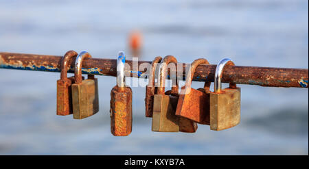 Rusty Vorhängeschlösser Verschlüsse auf geschälte Geländer. Tradition für ein paar in der Liebe. Blur Hintergrund, Nahaufnahme, Detail Stockfoto