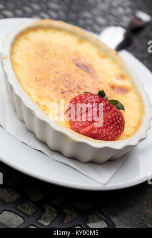 Süß und cremig Pudding Dessert aus Ei, Milch und Zucker, gekrönt mit einem in Scheiben geschnittene Erdbeeren in eine weiße Platte Stockfoto