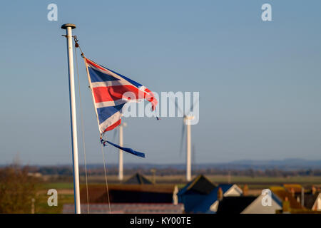 Ein tattered Union Jack Flagge im Wind flattern vor blauem Himmel. Stockfoto