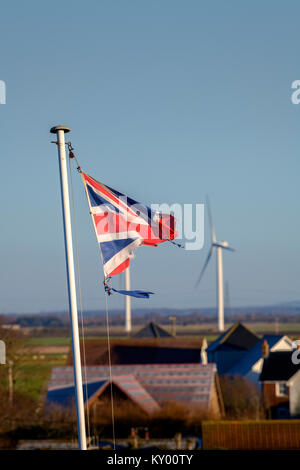 Ein tattered Union Jack Flagge im Wind flattern vor blauem Himmel. Stockfoto