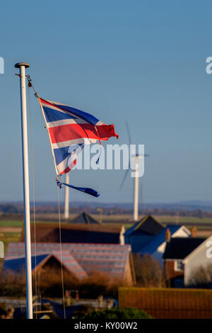 Ein tattered Union Jack Flagge im Wind flattern vor blauem Himmel. Stockfoto