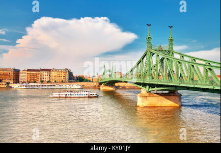 Budapest an einem hellen Tag. Passagierschiff unter Liberty Bridge oder Freiheit Brücke zwischen Buda und Pest über der Donau. Stockfoto