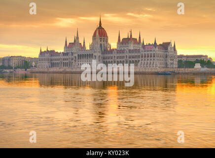 Das Parlamentsgebäude in Budapest, Ungarn, auf einem goldenen Sonnenaufgang mit Reflexion im Fluss Stockfoto