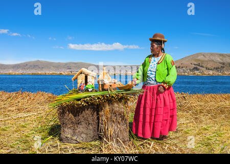 PUNO, PERU - 14. MAI 2015: Nicht identifizierte Frau in traditioneller Kleidung, Kunsthandwerk in der Uros Inseln. Stockfoto