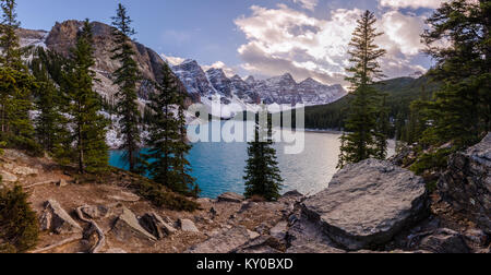 Moraine Lake im Banff National Park bei Sonnenuntergang mit Wolken, Berge, Bäume und Felsen Stockfoto