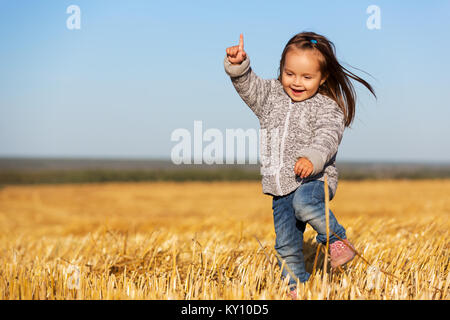 Happy 2 jähriges Mädchen zu Fuß in einer Sommer geernteten Feld Stockfoto