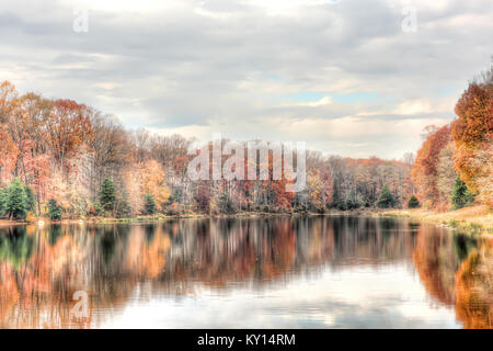 Sonnenuntergang am See Woodglen in Fairfax, Virginia in der Nähe von Wohngebiet, mit orange Laub Herbst Bäume Wald, Wasser Reflexion, Häuser, rocky b Stockfoto