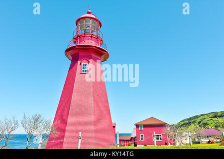 Rot lackiert Leuchtturm mit gelben Löwenzahn Blumen in La Martre in der gaspe Halbinsel, Quebec, Kanada, Gaspesie region Stockfoto