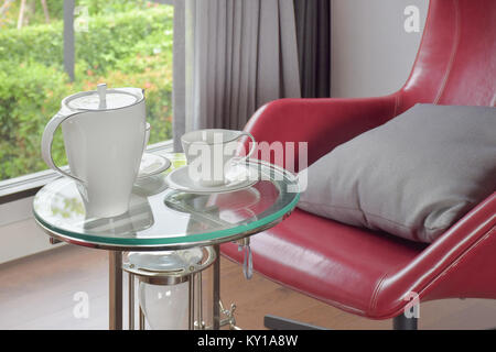 Teeservice auf Glas Tisch mit roten Sessel im Wohnzimmer Stockfoto