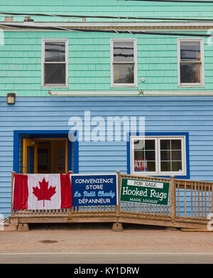 Kanadische Flagge und Speichern von Zeichen außerhalb bunte Holzhaus, Cheticamp, Cape Breton Island, Nova Scotia, Kanada Stockfoto