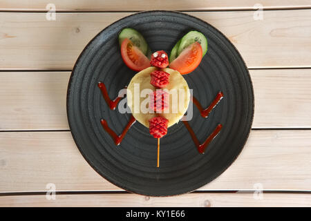 Lustig Essen für Kinder. Kartoffelpüree mit gebratenen Würstchen am Spieß mit Tomaten und Gurken Stockfoto