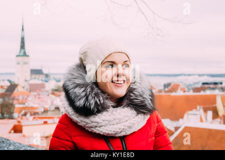 Tallinn, Estland. Junge schöne Hübsche kaukasische Mädchen Frau gekleidet im roten Mantel und dem weißen Hut das Leben genießen Und lächelnd auf der Aussichtsplattform auf Bac Stockfoto