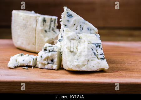 Dänische blau oder Roquefort Käse Makroaufnahme auf dem Schneidbrett mit groben Kanten und schimmelig Venen ausgesetzt. Stockfoto