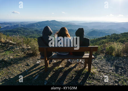 Foto von zwei Männer und eine Frau von hinten sitzt auf der Bank Stockfoto