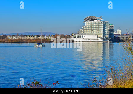 Eine kleine Yacht kehrt nach Hause zurück nach Cardiff Bay, vorbei an der St. David Hotel, ein 5 Sterne luxus Hotel durch den Auftraggeber Hotel Company. Stockfoto
