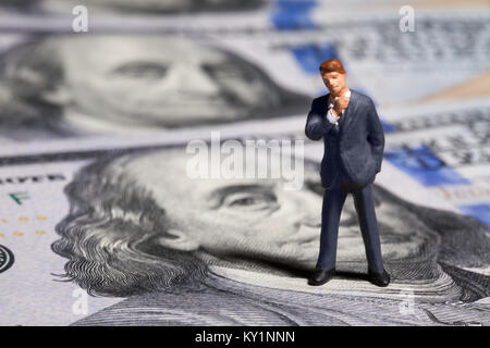 Miniatur Figur Geschäftsmann mit 100 Dollar Banknote auf Hintergrund Stockfoto