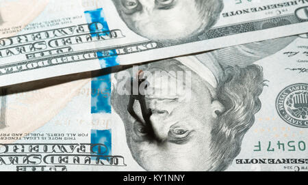 Miniatur Figur Geschäftsmann mit 100 Dollar Banknote auf Hintergrund Stockfoto