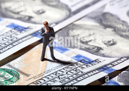 Miniatur Figur Geschäftsmann mit 100 Dollar Banknote auf Hintergrund Stockfoto