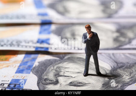 Miniatur Figur Geschäftsmann mit 100 Dollar Banknote auf Hintergrund Stockfoto