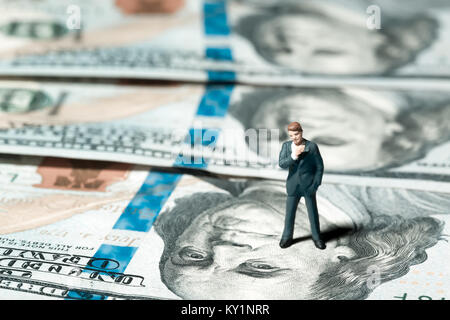 Miniatur Figur Geschäftsmann mit 100 Dollar Banknote auf Hintergrund Stockfoto