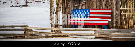 Eine patriotische Bank sitzt vor einer Hütte im Wisconsin Landschaft. Stockfoto