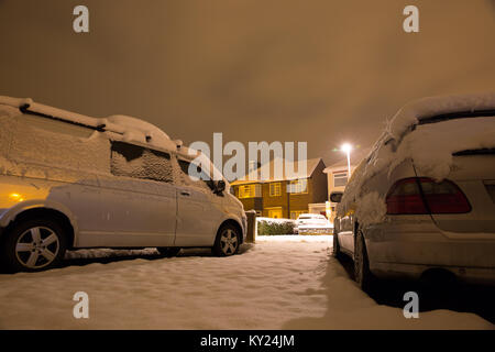 Verschneite Straße Szene auf einem kalten Dezember Abend, von der Einfahrt zu einem der Häuser. Straße Licht erstrahlt. Alle ruhig, alles ist weiß. Stockfoto