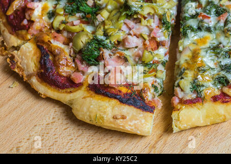 Frische Pizza serviert auf einem rustikalen Holztisch. Stockfoto