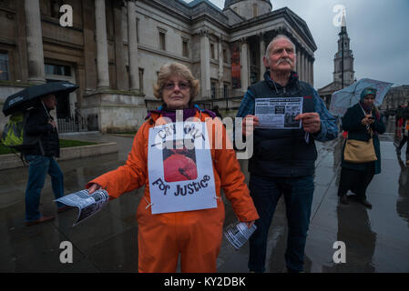 Januar 11, 2018 - London, UK. 11. Januar 2018. Demonstranten in Orange springen Anzüge und schwarze Hauben stehen in einem Quadrat am Trafalgar Square Kennzeichnung 16 Jahre die illegale Inhaftierung und Folter Lager in Guantanamo Bay. Die Namen der 41 verbleibenden Häftlinge wurden ausgelesen, viele ohne Anklage oder Gerichtsverfahren auf unbestimmte Zeit gehalten, fast alle, die in die USA um afghanischen Milizen verkauft wurden und das pakistanische Militär für Bargeld Prämien ohne wirkliche Beweise für terroristische Aktivitäten, aber deren Folter in CIA geheime Gefängnisse in der ganzen Welt vor der Ankunft in Guantanamo als auch während ihrer Haft es Macht Stockfoto