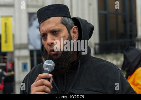 Januar 11, 2018 - London, UK. 11. Januar 2018. Demonstranten in Orange springen Anzüge und schwarze Hauben stehen in einem Quadrat am Trafalgar Square Kennzeichnung 16 Jahre die illegale Inhaftierung und Folter Lager in Guantanamo Bay. Die Namen der 41 verbleibenden Häftlinge wurden ausgelesen, viele ohne Anklage oder Gerichtsverfahren auf unbestimmte Zeit gehalten, fast alle, die in die USA um afghanischen Milizen verkauft wurden und das pakistanische Militär für Bargeld Prämien ohne wirkliche Beweise für terroristische Aktivitäten, aber deren Folter in CIA geheime Gefängnisse in der ganzen Welt vor der Ankunft in Guantanamo als auch während ihrer Haft es Macht Stockfoto