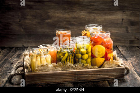 Anders haltbar gemacht Gemüse aus Gemüse und Pilzen, die in Gläsern. Auf einer hölzernen Hintergrund. Stockfoto