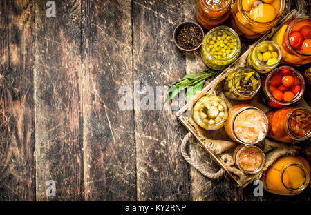 Anders haltbar gemacht Gemüse aus Gemüse und Pilzen, die in Gläsern. Auf einer hölzernen Hintergrund. Stockfoto