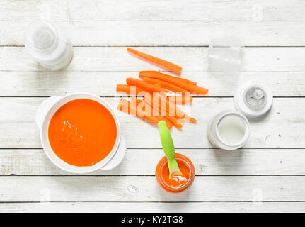 Babynahrung. Baby Karotten Püree mit Milch in der Flasche. Auf einem weißen Holz- Hintergrund. Stockfoto