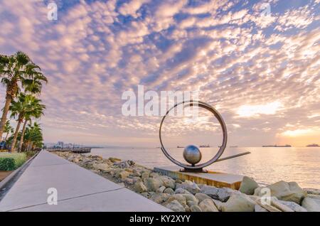 Molos Promenade und Skyline von der Küste in Limassol Stadt in Zypern bei Sonnenaufgang. Blick auf die Skulptur Wahrzeichen, Boardwalk pier Weg mit Palmen, p Stockfoto